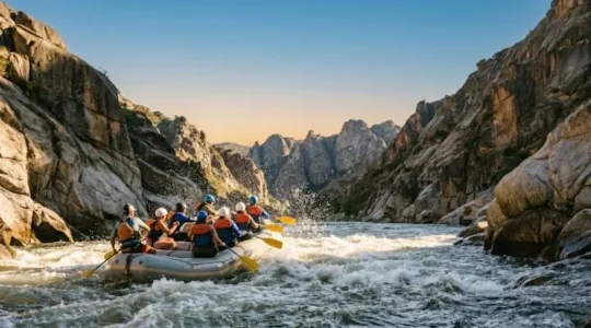 A raft crew paddling together through a foaming rapid, framed by canyon walls, symbolizing the choice of a first whitewater adventure