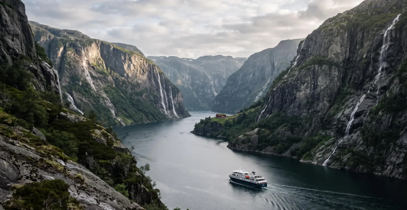 A small fjord cruise vessel navigating between towering cliffs on a Norwegian fjord at golden hour